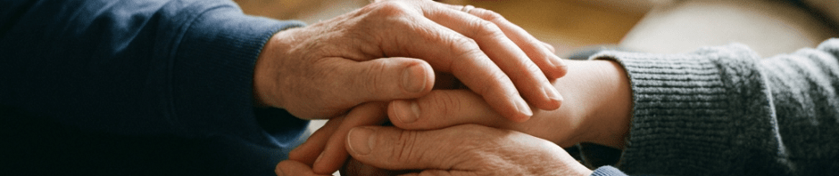 Two pairs of hands gently holding each other in a comforting gesture