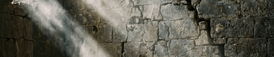 Stone chamber with cracked walls and sunlight beams shining through an arched opening, illuminating a wooden stool