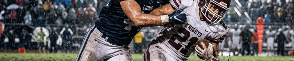 High school football players in rain battling on a muddy field